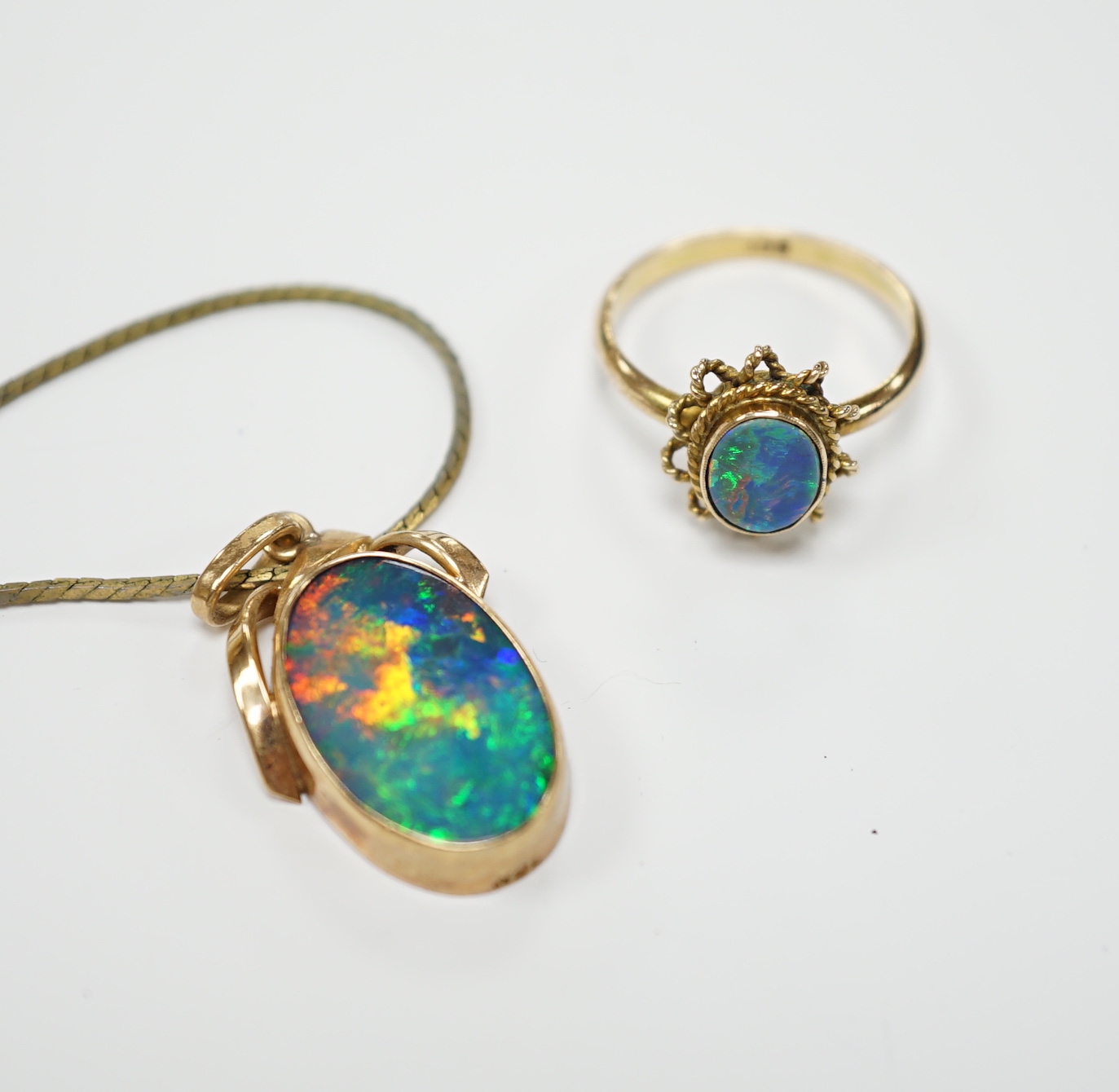 A 9ct and black opal doublet set oval ring, size L and a yellow metal and black opal doublet set pendant, on a gilt metal chain.